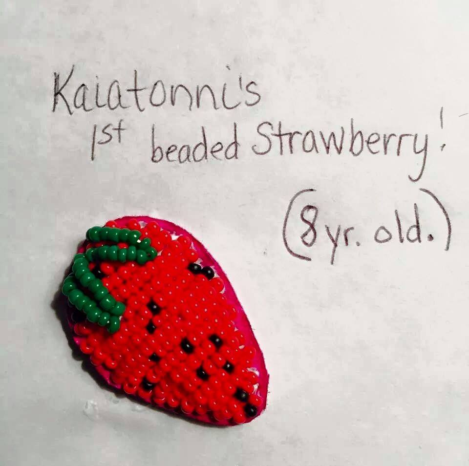 Beaded strawberry on paper that reads "Kaiatonni's 1st Beaded Strawberry! (8 yr. old.)"